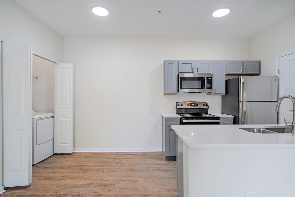 a white kitchen with stainless steel appliances and a white counter top