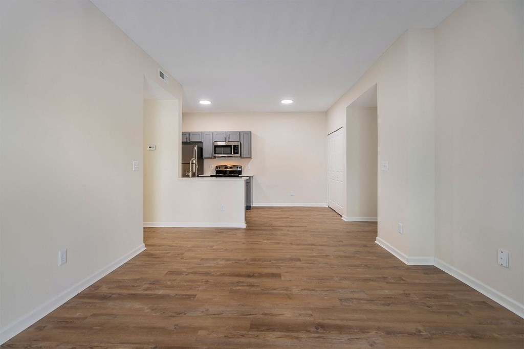 a living room and kitchen with white walls and wood floors