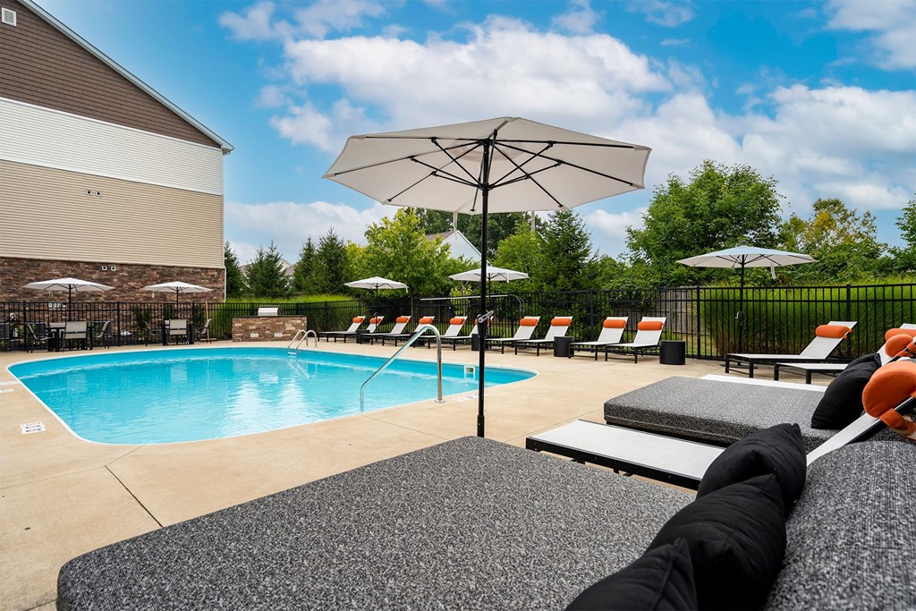 outdoor pool with umbrella and lounge chairs