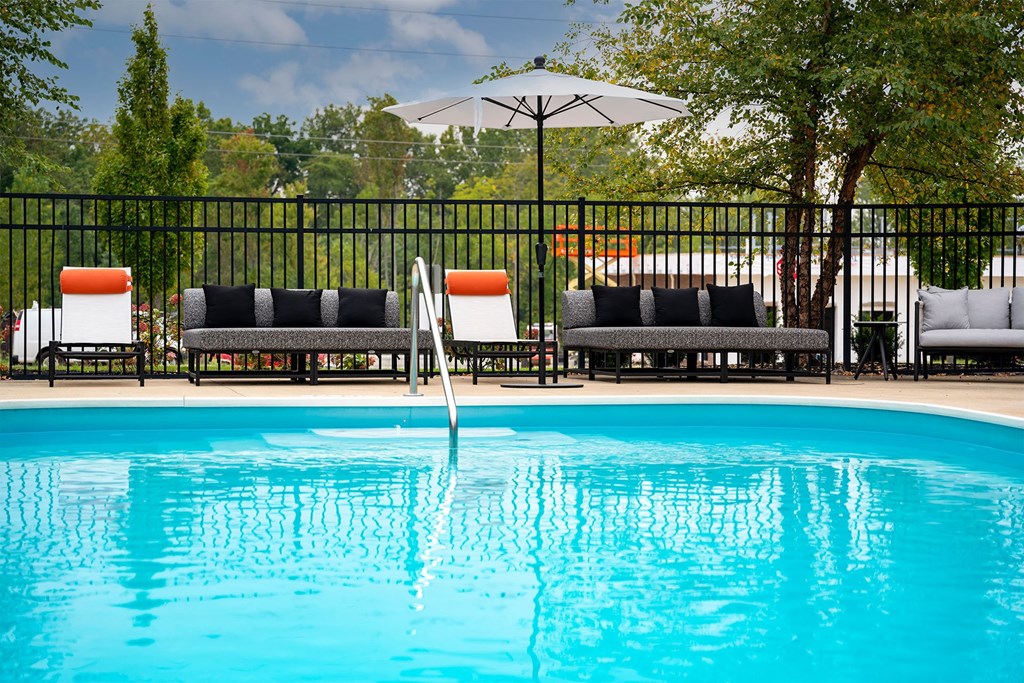 a swimming pool with chairs and a umbrella next to a resort pool