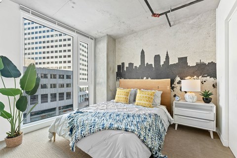 a bedroom with a bed and a city mural on the wall