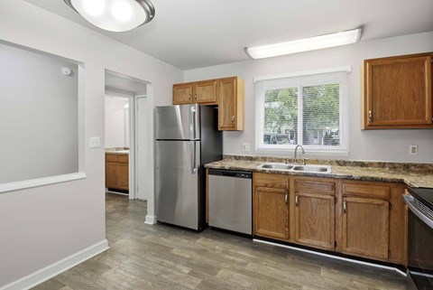 A kitchen with a refrigerator, sink, and cabinets.