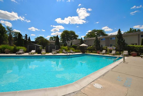 A large swimming pool with a blue tinted water and a white fence around it.