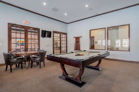 A room with a pool table and a table with chairs.