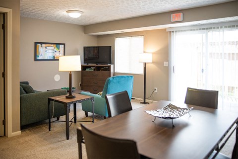 A living room with a couch, chairs, a table, a television, and a painting on the wall.