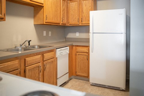 A white refrigerator stands in a kitchen with wooden cabinets.