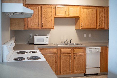 A kitchen with a white stove top oven and a white microwave.