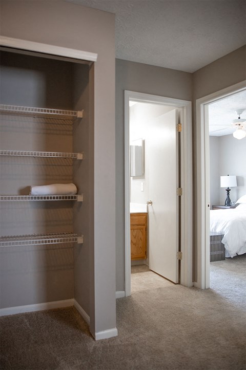 A bedroom with a white bed and a walk-in closet.
