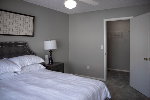 A bedroom with a bed, nightstand, and a ceiling fan.