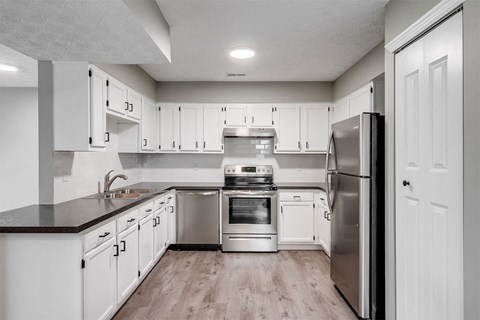 A modern kitchen with white cabinets and stainless steel appliances.