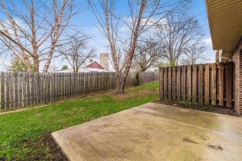 A backyard with a wooden fence and a concrete patio.