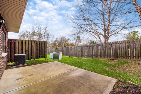A backyard with a wooden fence and a green container.