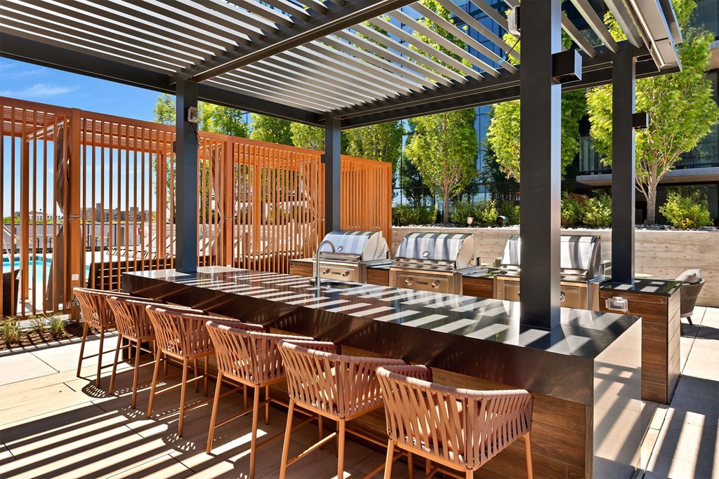 A long wooden table is surrounded by chairs under a roof.