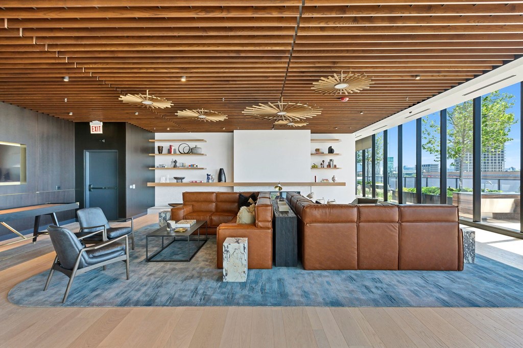a living room with brown leather couches and chairs and a blue rug
