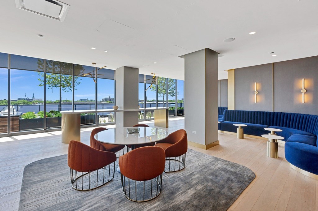 a lounge area with blue couches and a glass table with chairs