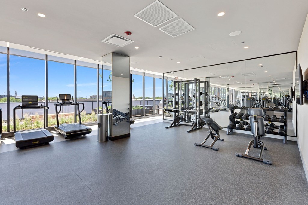 a gym with floor to ceiling windows and weights and cardio equipment