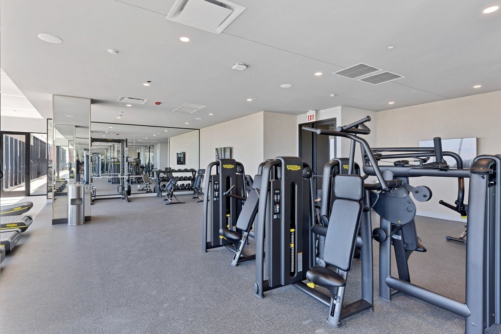 a gym with weights and cardio equipment in a building with glass walls