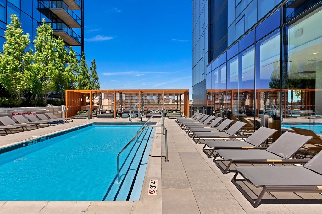 a pool with lounge chairs next to a glass building