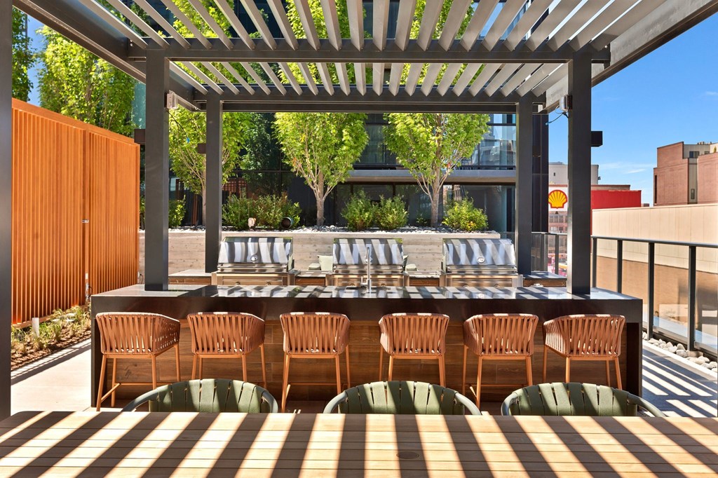 a patio with chairs and a bar under a pergola