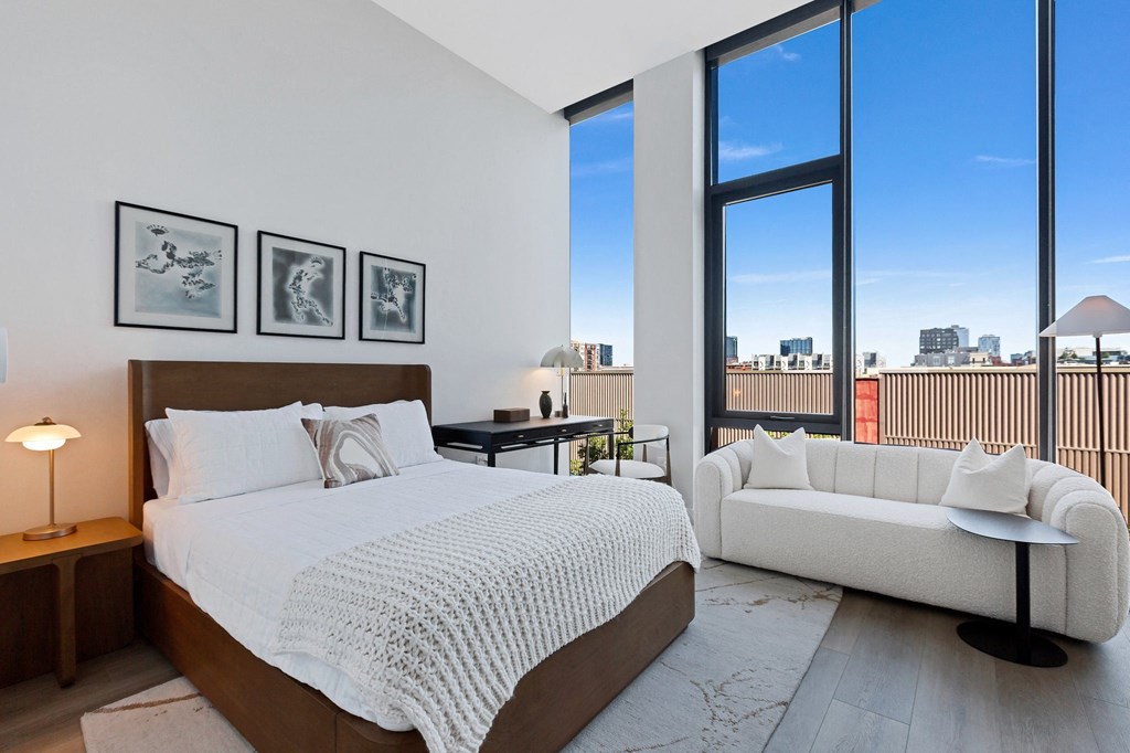 a bedroom with a bed and a couch and tall windows