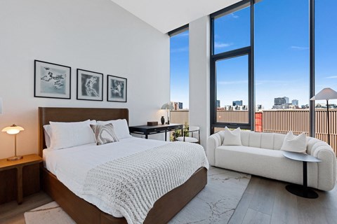 a bedroom with a bed and a couch and tall windows