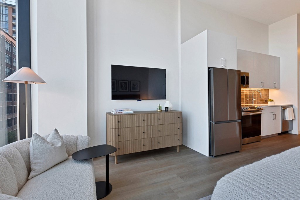 a living room with a couch and a kitchen with a refrigerator