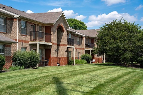 A large brick apartment building with a green lawn in front.