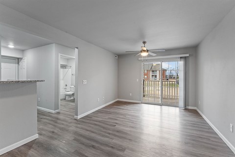 A spacious room with a sliding glass door leading to a balcony.