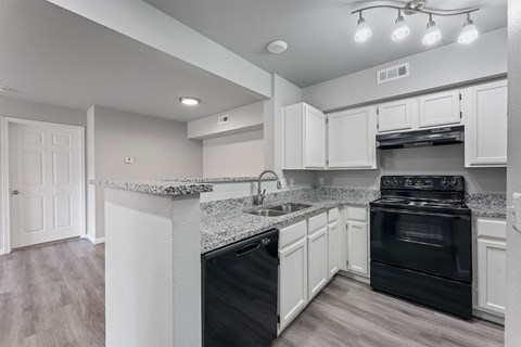 A kitchen with black appliances and white cabinets.