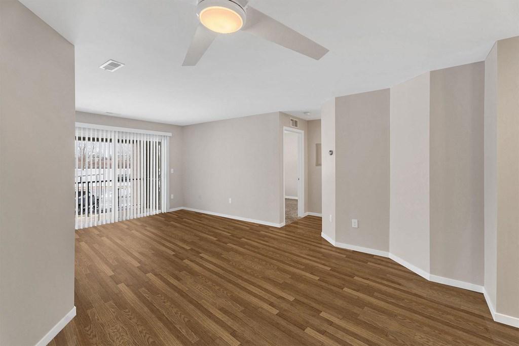 A room with a ceiling fan and wooden flooring.