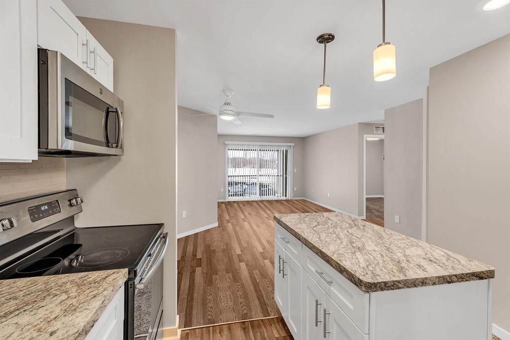 A kitchen with a granite counter top and wooden flooring.