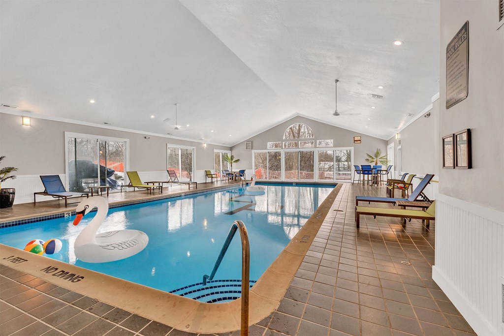 A large indoor swimming pool with a slide and lounge chairs.