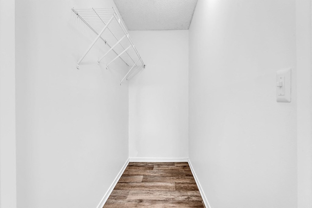 A white wall with a light switch and a white shelf.