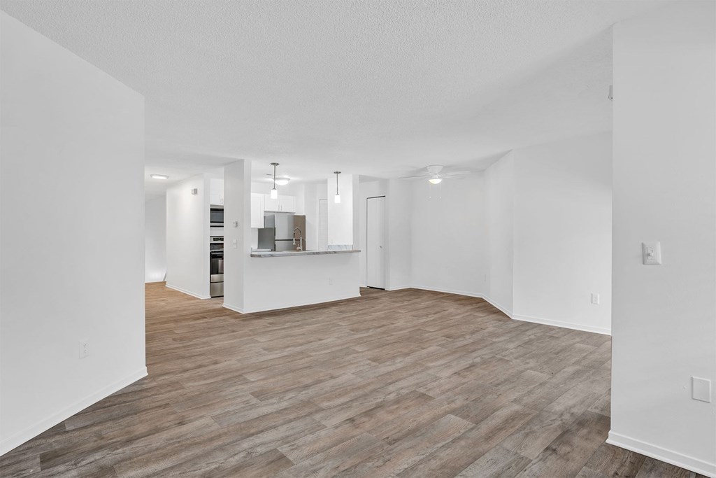A spacious room with wooden flooring and white walls.
