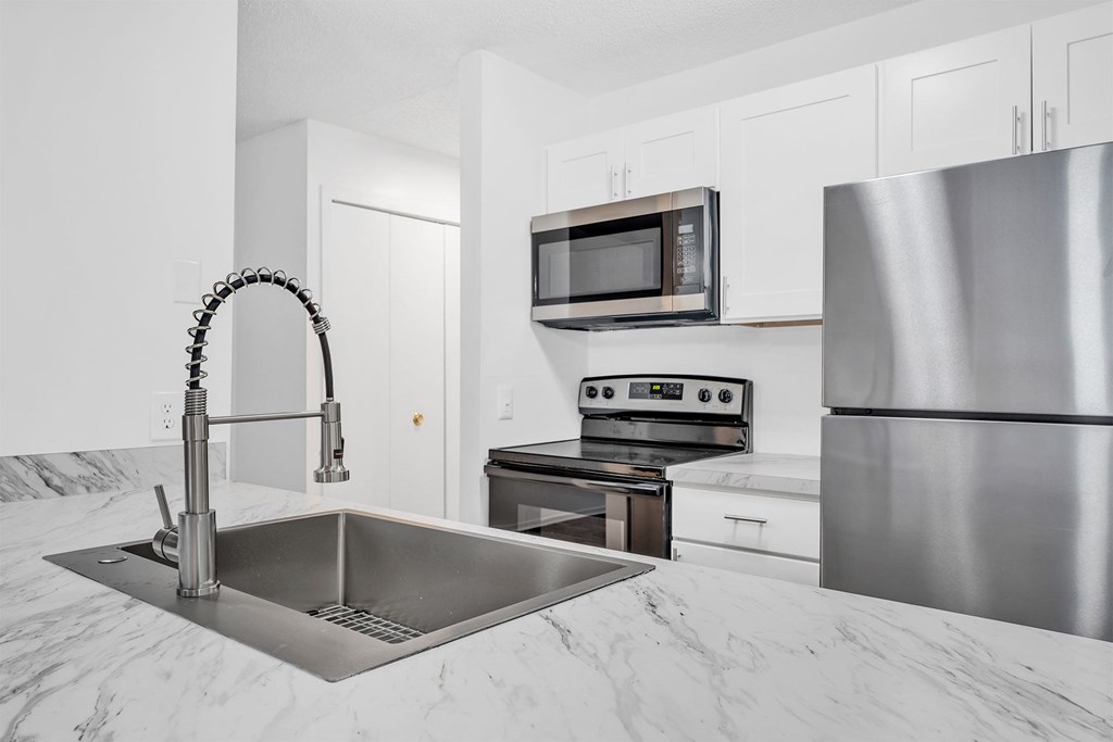 A modern kitchen with a stainless steel refrigerator, microwave, and oven.