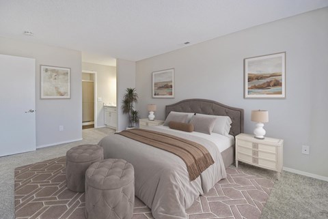 A bedroom with a large bed and a nightstand with a lamp.