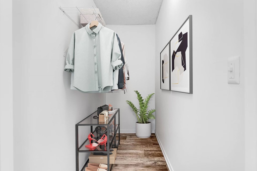 A white shirt hanging on a wall next to a potted plant.