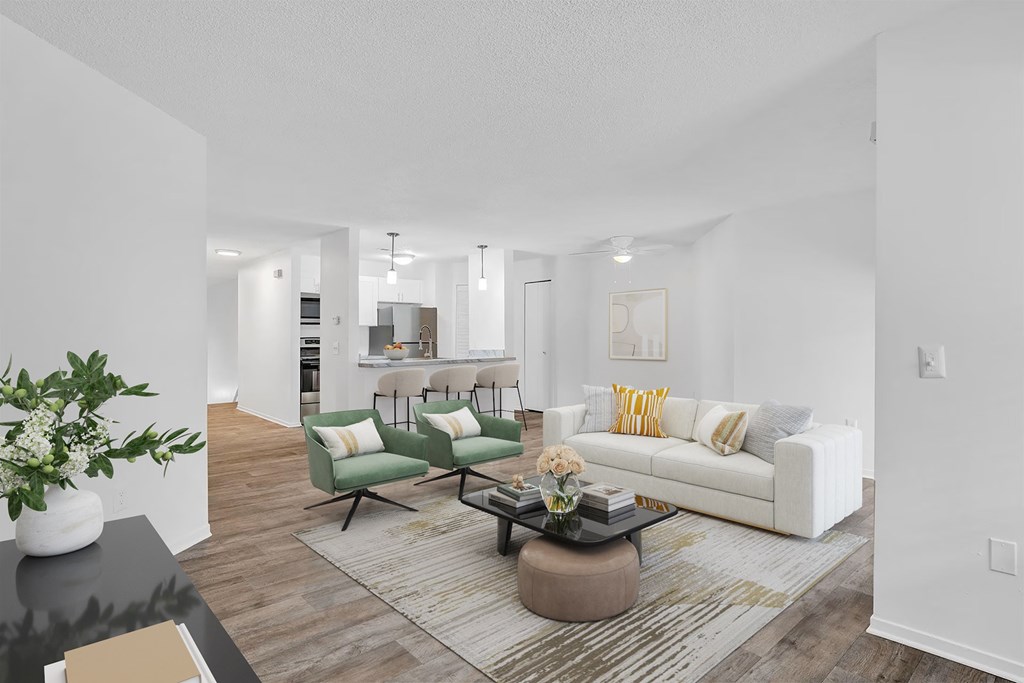A modern living room with a white sofa, green armchair, and a coffee table.