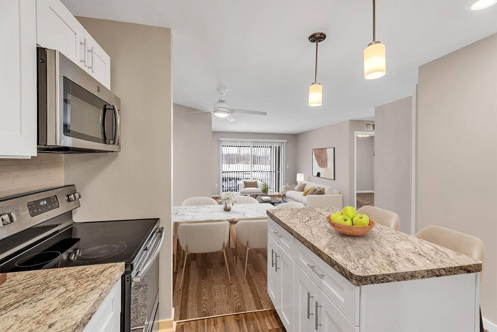 A kitchen with a granite countertop and a dining area with a table and chairs.