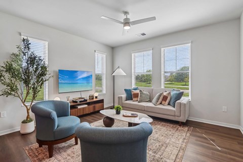 A living room with a blue chair, a grey sofa, a wooden coffee table, and a painting on the wall.