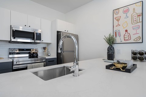 A modern kitchen with a stainless steel sink and a fridge.