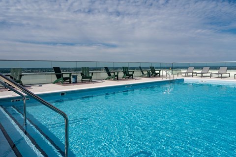 A swimming pool with a metal railing and chairs.