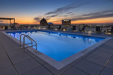 A swimming pool on a rooftop with a sunset in the background.