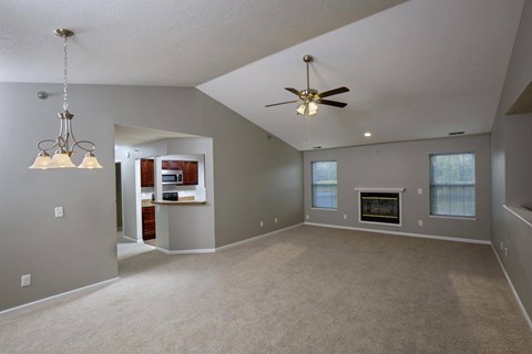 A spacious living room with a fireplace and a ceiling fan.