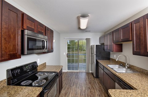 A kitchen with a black stove top oven and wooden cabinets.