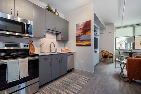 A modern kitchen with a stove top oven and a painting on the wall.
