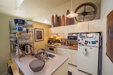 A kitchen with a white refrigerator and a white sink.