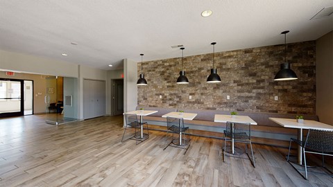 a dining room with tables and chairs and a stone wall