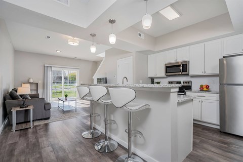 A modern kitchen with a bar area and a living room area.