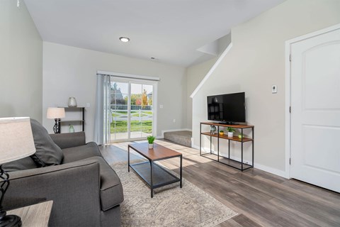 A living room with a grey couch, a coffee table, and a television.